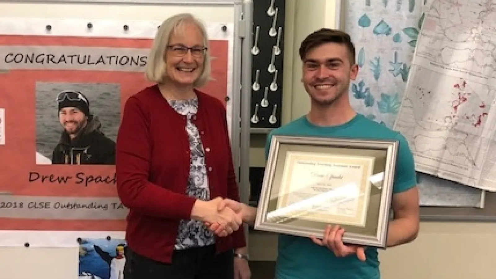 Caroline Breitenberger congratulates 2018 CLSE Outstanding TA Drew Spacht with a handshake and certificate